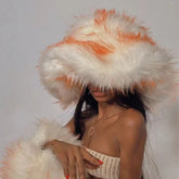Person wearing a large white and orange feathered hat against a plain background